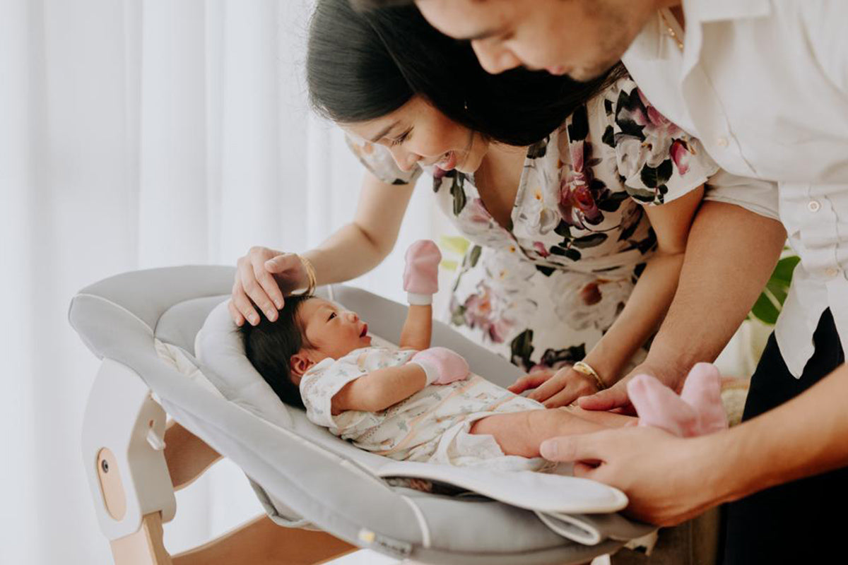 parents playing with their newborn baby in Hauck’s Alpha Bouncer