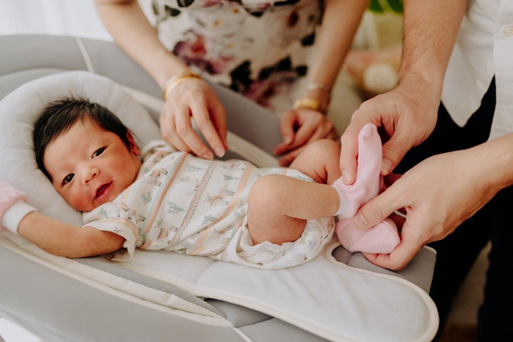 parents taking care of happy baby on infant bouncer