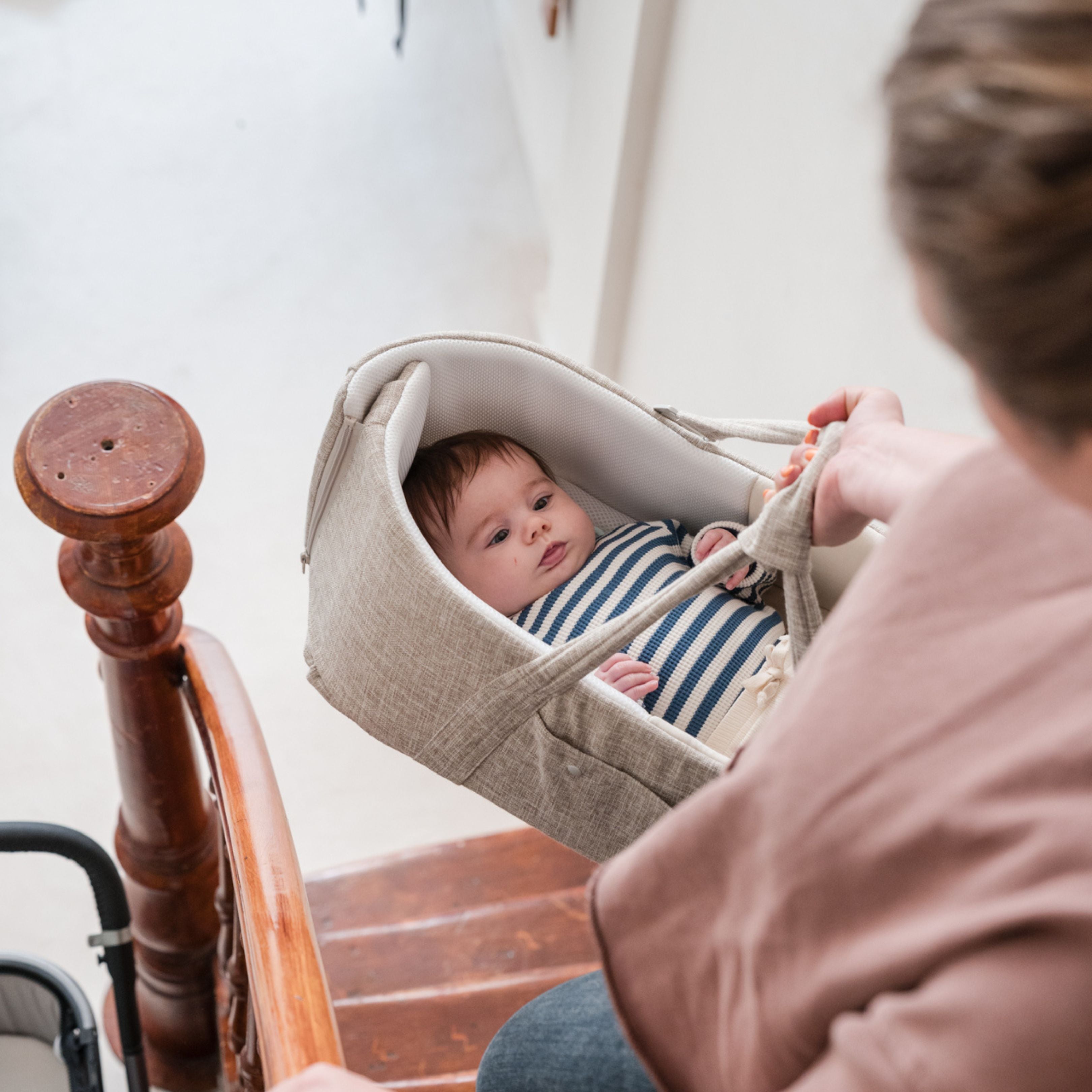 mum carrying baby in the doomoo nest n go walking down the stairs