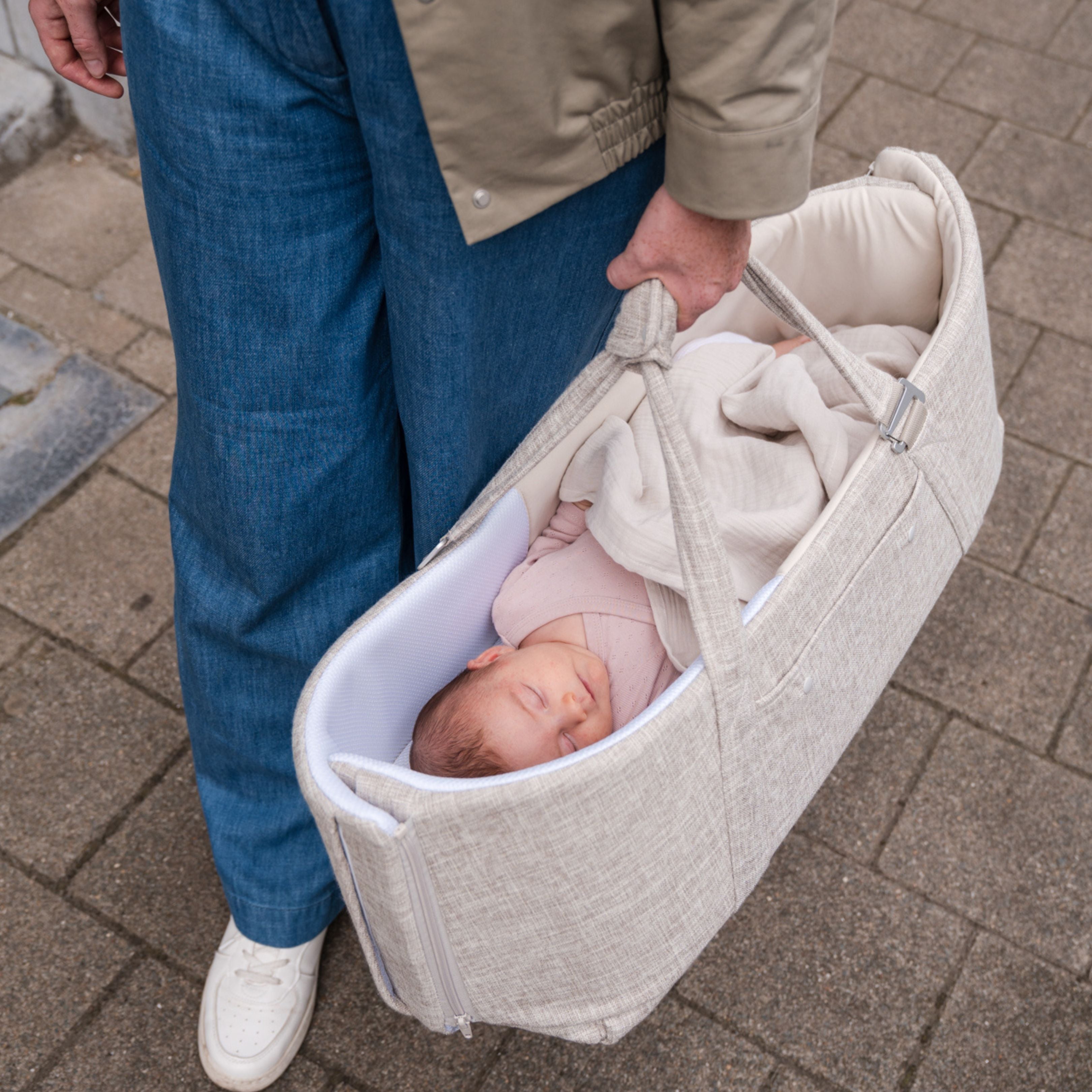 parent carrying baby out in the doomoo nest n go as she sleeps comfortably