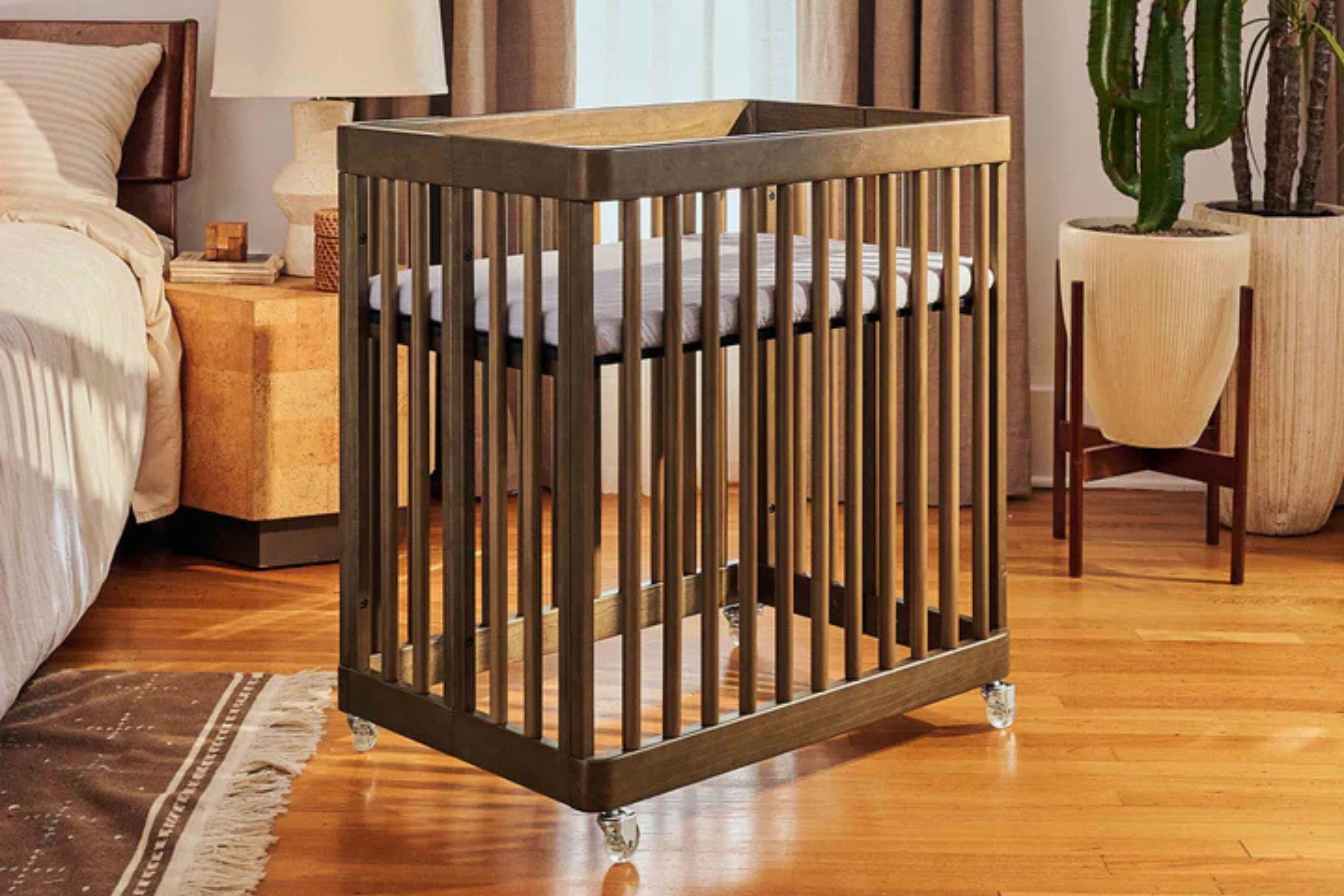 Babyletto natural walnut pogo 8-in-1-convertible crib bassinet wheeled into a nursery#color_walnut