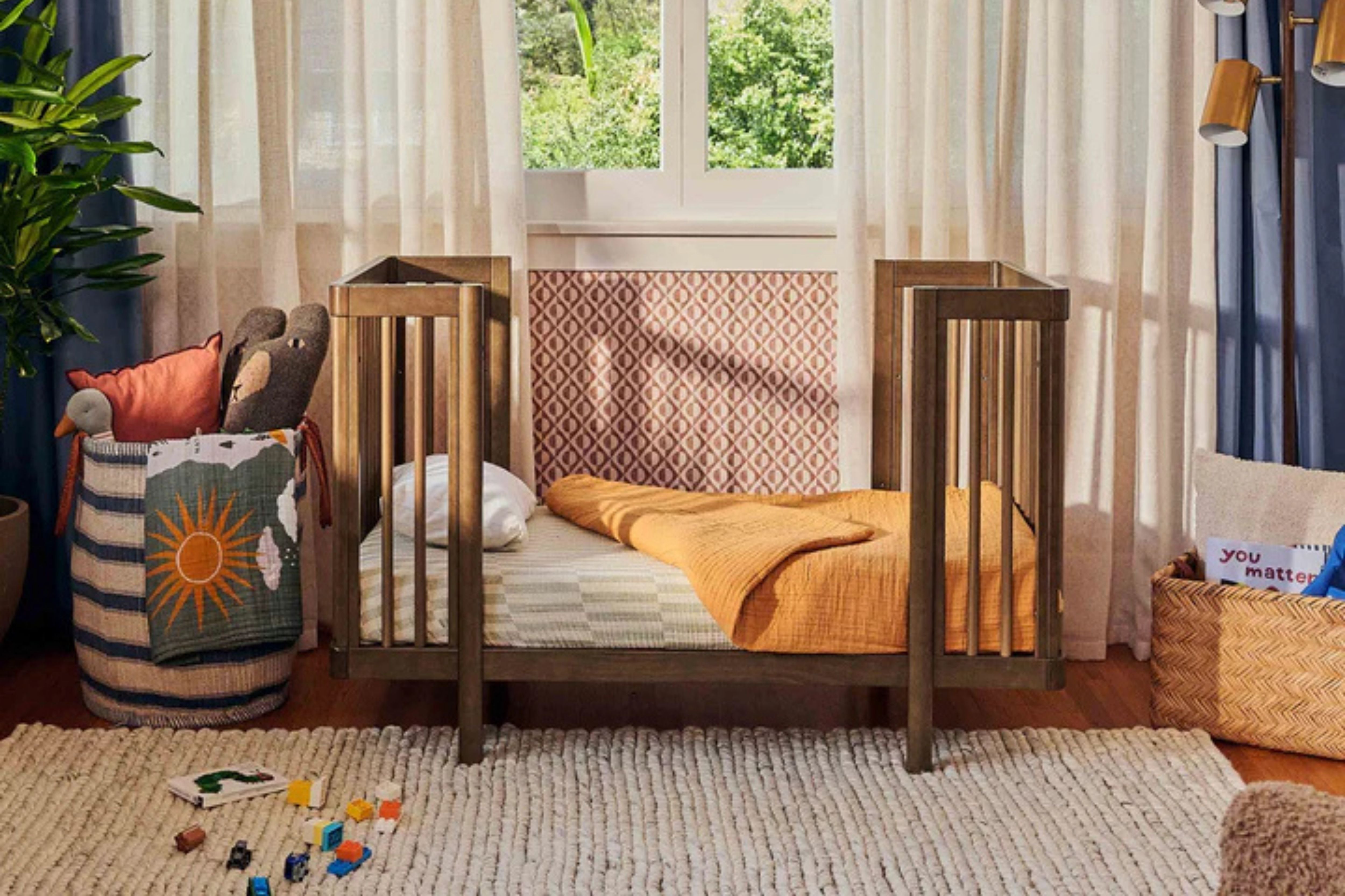 Babyletto natural walnut pogo 8-in-1-convertible crib junior bed placed in a nursery#color_walnut