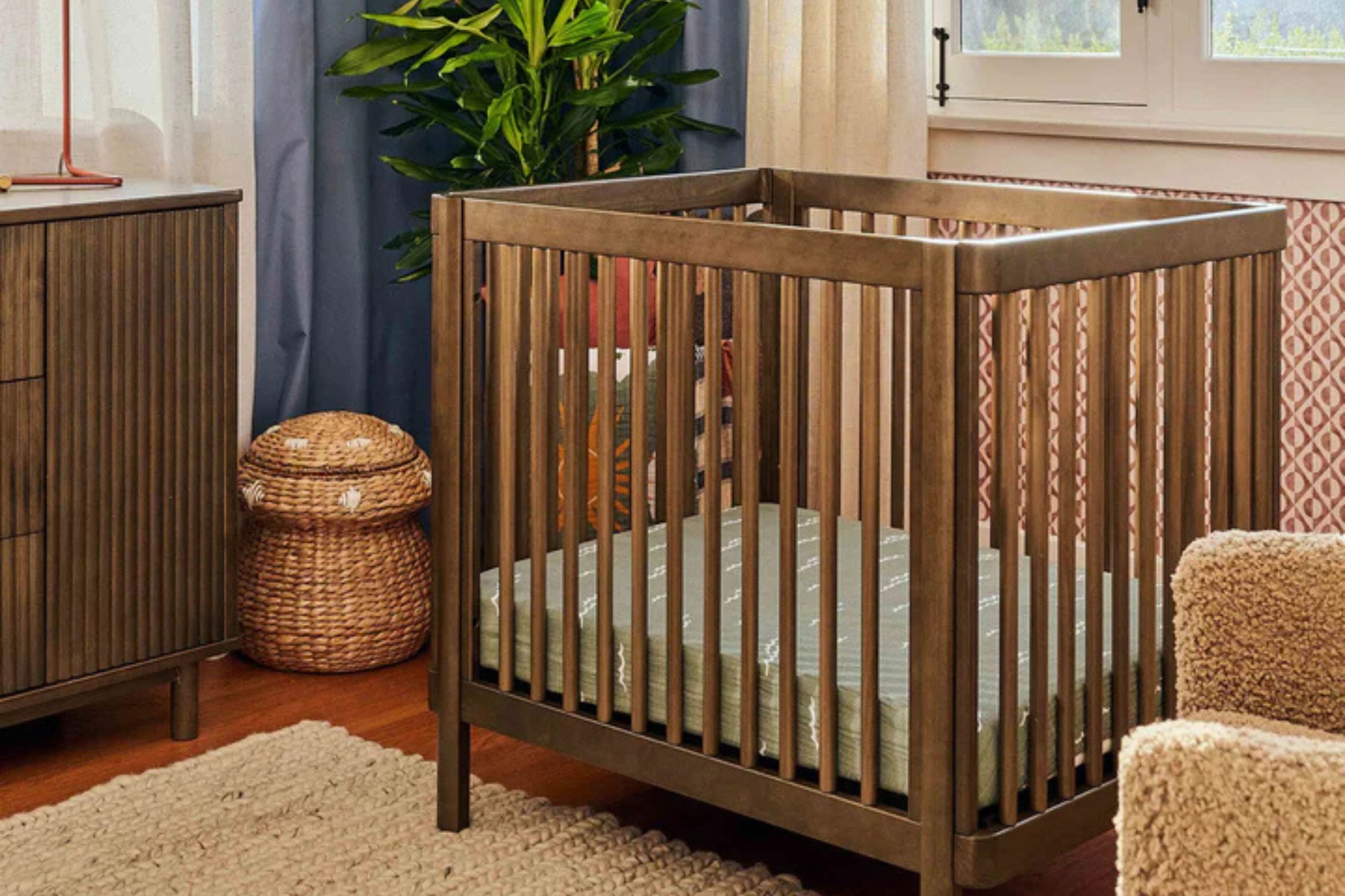 Babyletto natural walnut pogo 8-in-1-convertible crib midi displayed in a corner of a nursery#color_walnut