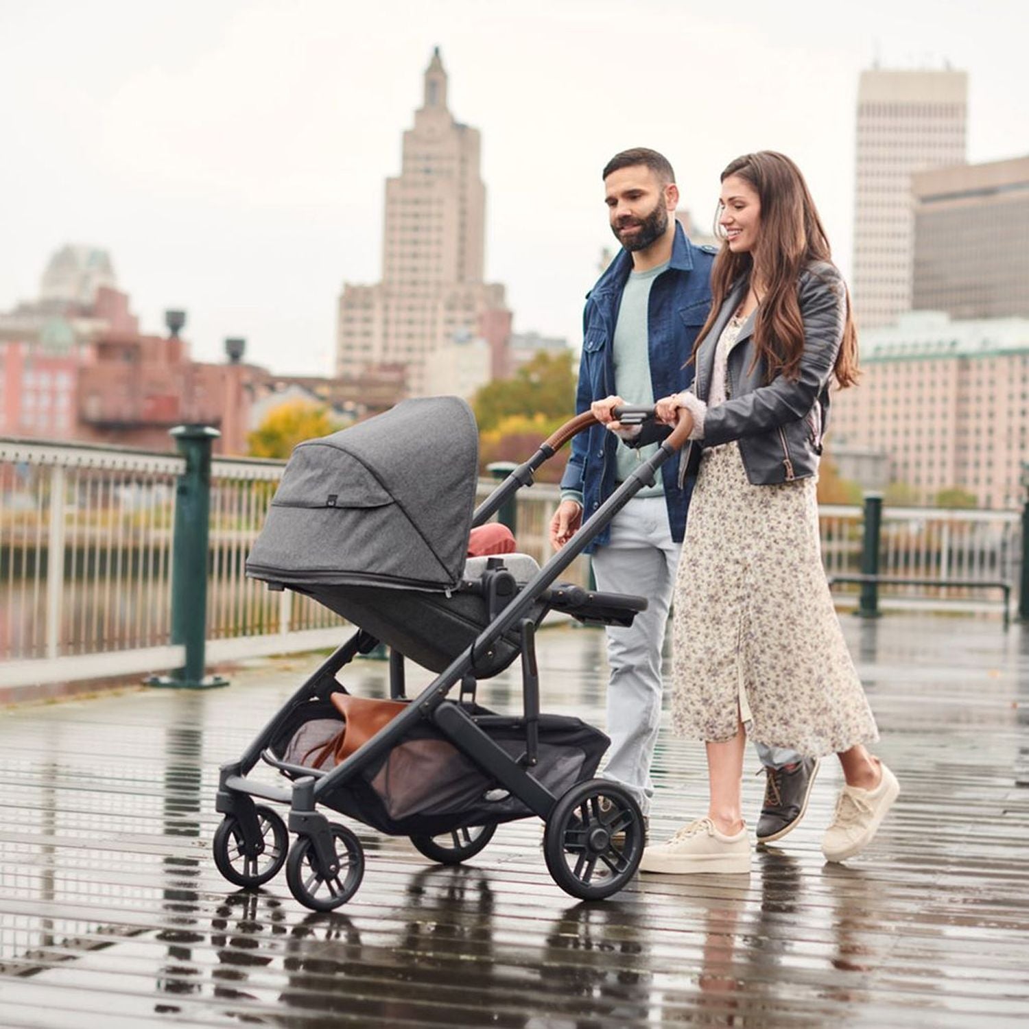 Parents taking their baby out on a stroll with the Uppababy Cruz 2 Greyson Reversible Stroller#color_greyson