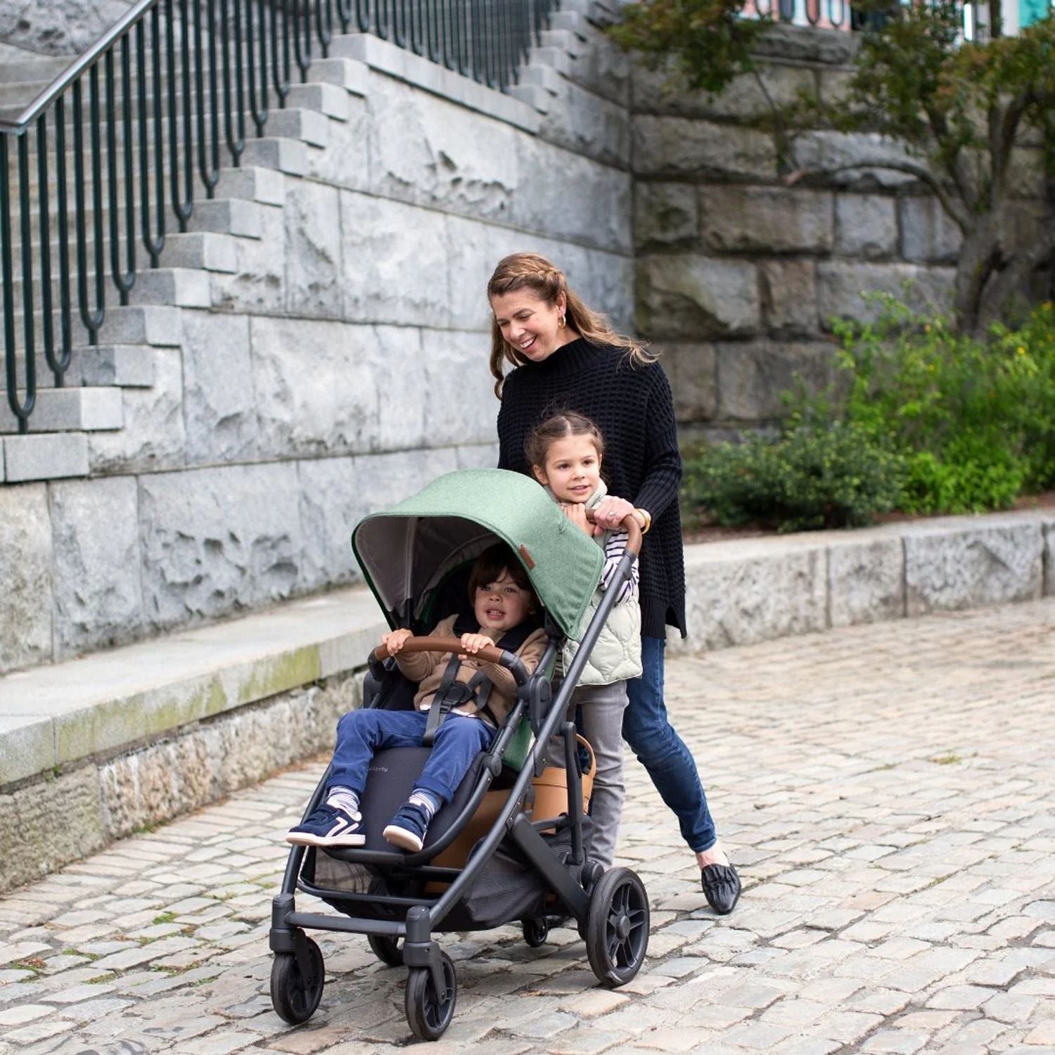 Mum taking her two kids out on the Uppababy Cruz 2 Gwen Reversible Stroller #color_gwen