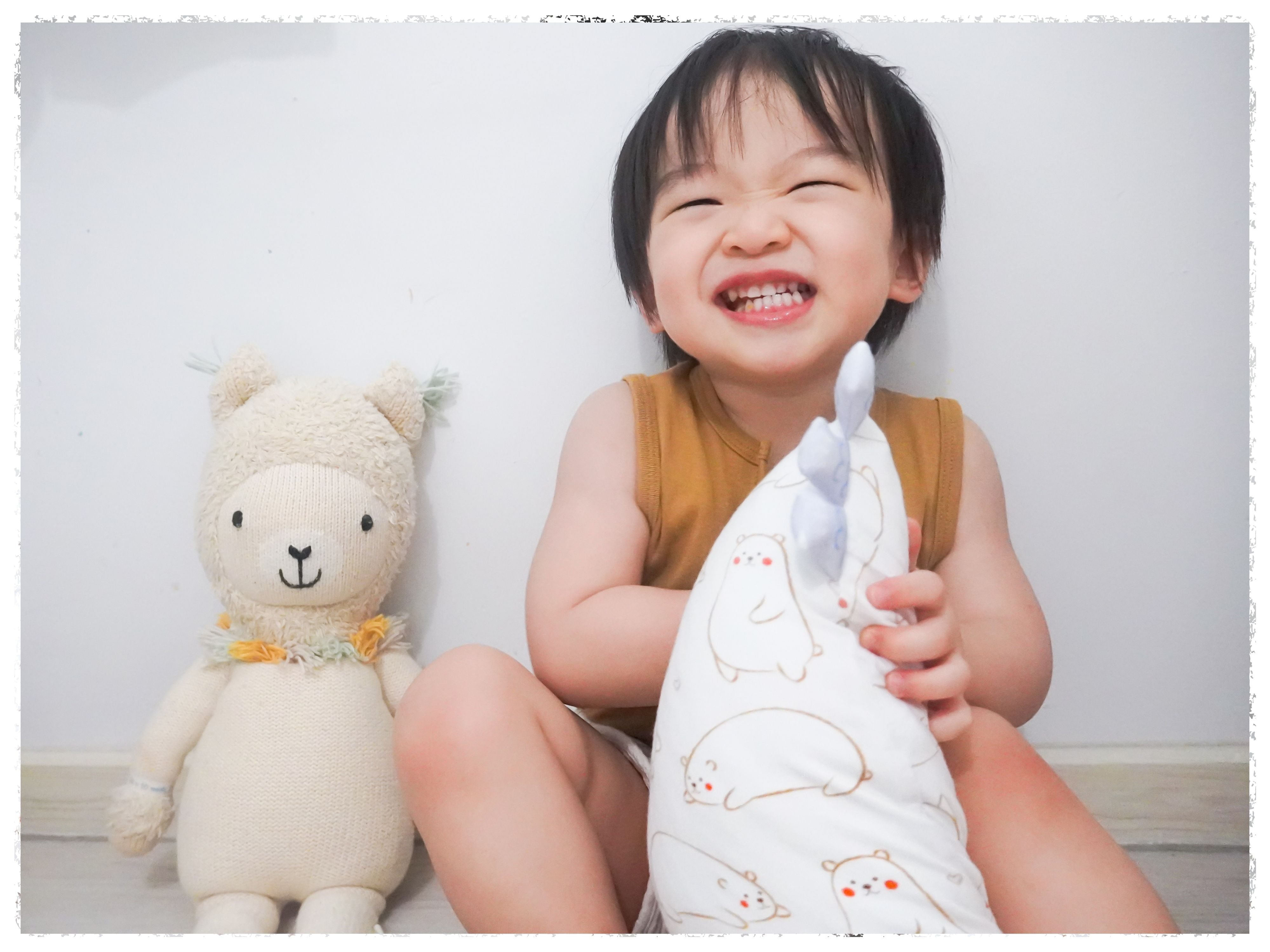 baby smiling while gripping to small cho maru bear pillow