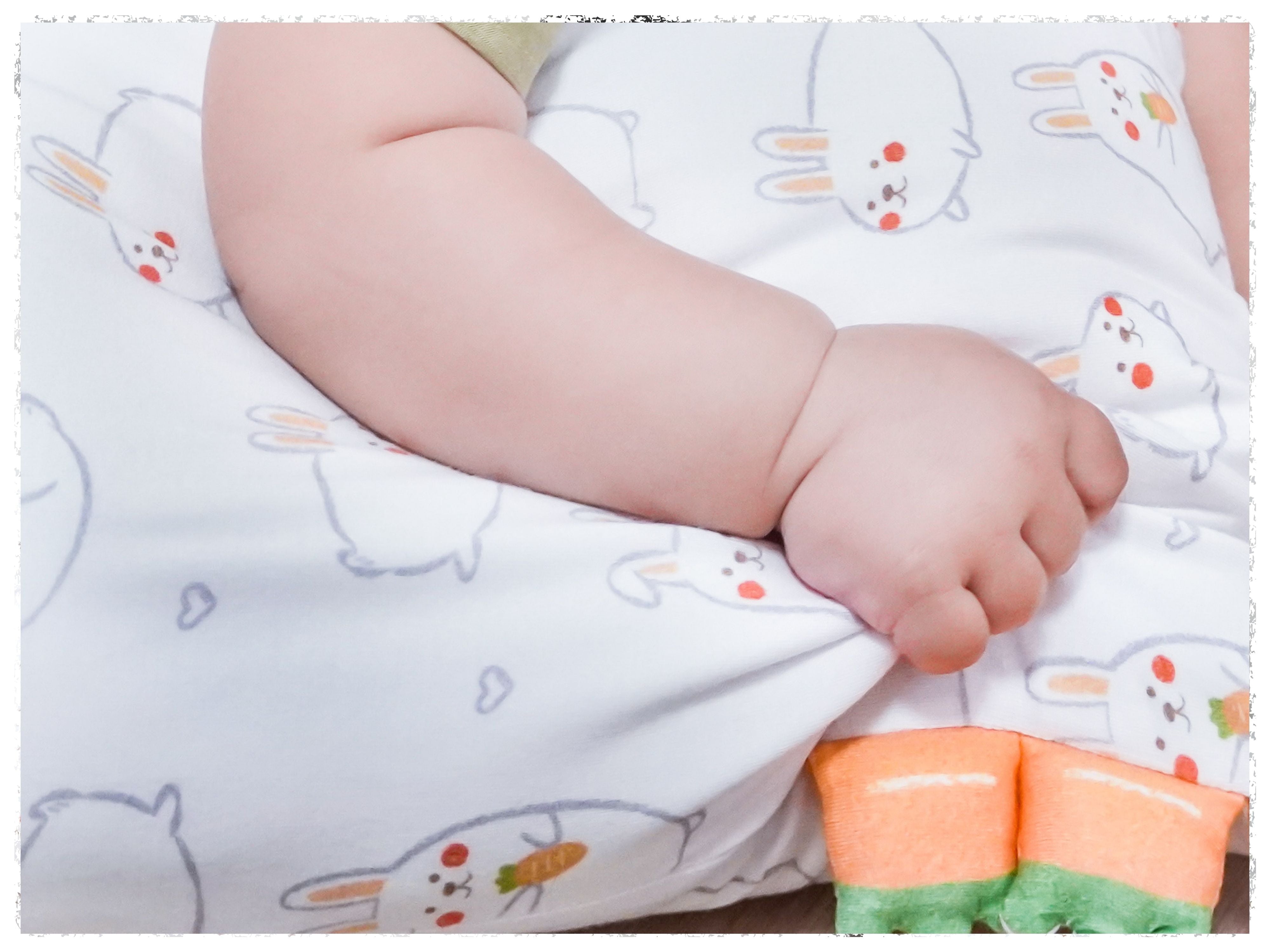 baby gripping onto a small cho momo bunny pillow