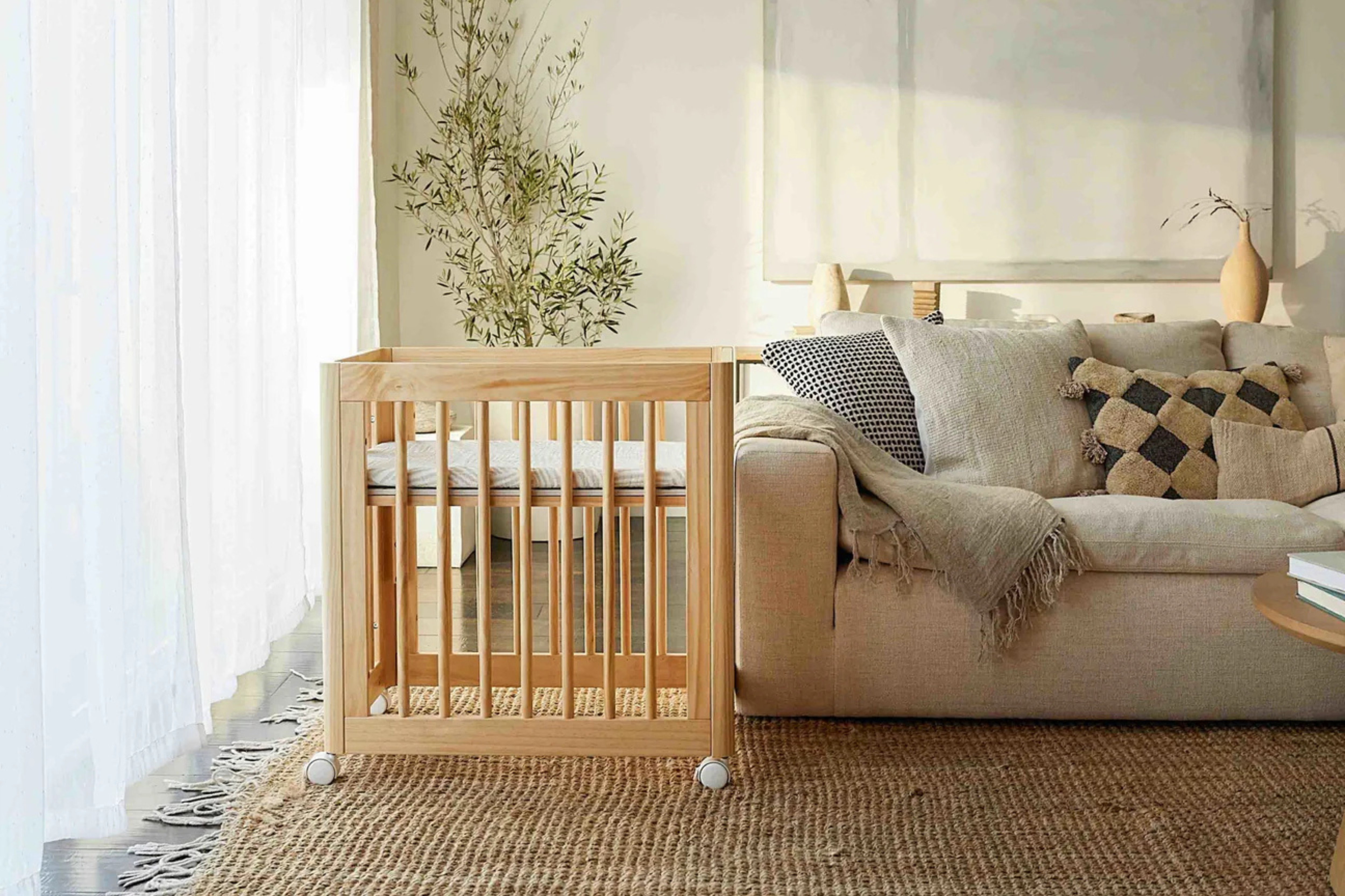 Babyletto Yuzu 8-in-1 Convertible Crib Natural in bassinet configuration placed in a living room#color_natural